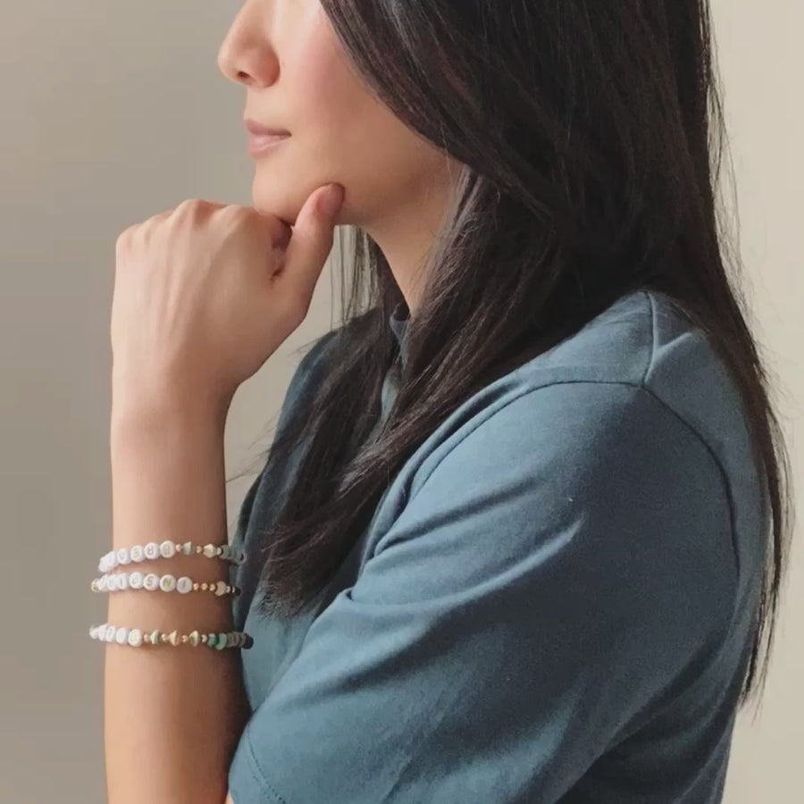 Ethically made stack of letter bead bracelets with word inspire