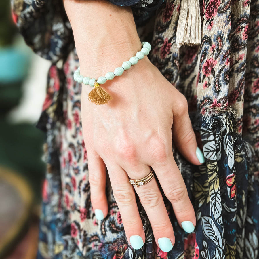 Ethically made bracelets that say M is for Mama and Hard does not equal badin navy, mint, multi colored, gold, charms, and tassels