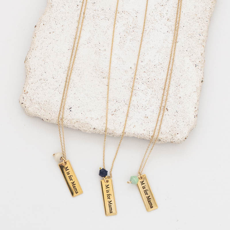 Ethically made 18k gold plated necklace with handmade paper bead and a bar pendant engraved with the phrase M is for Mama close up shot of three necklaces