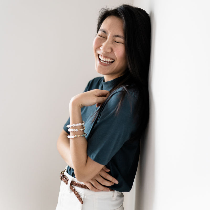 Woman wearing a stack of letter bead bracelets with three words dream inspire breathe